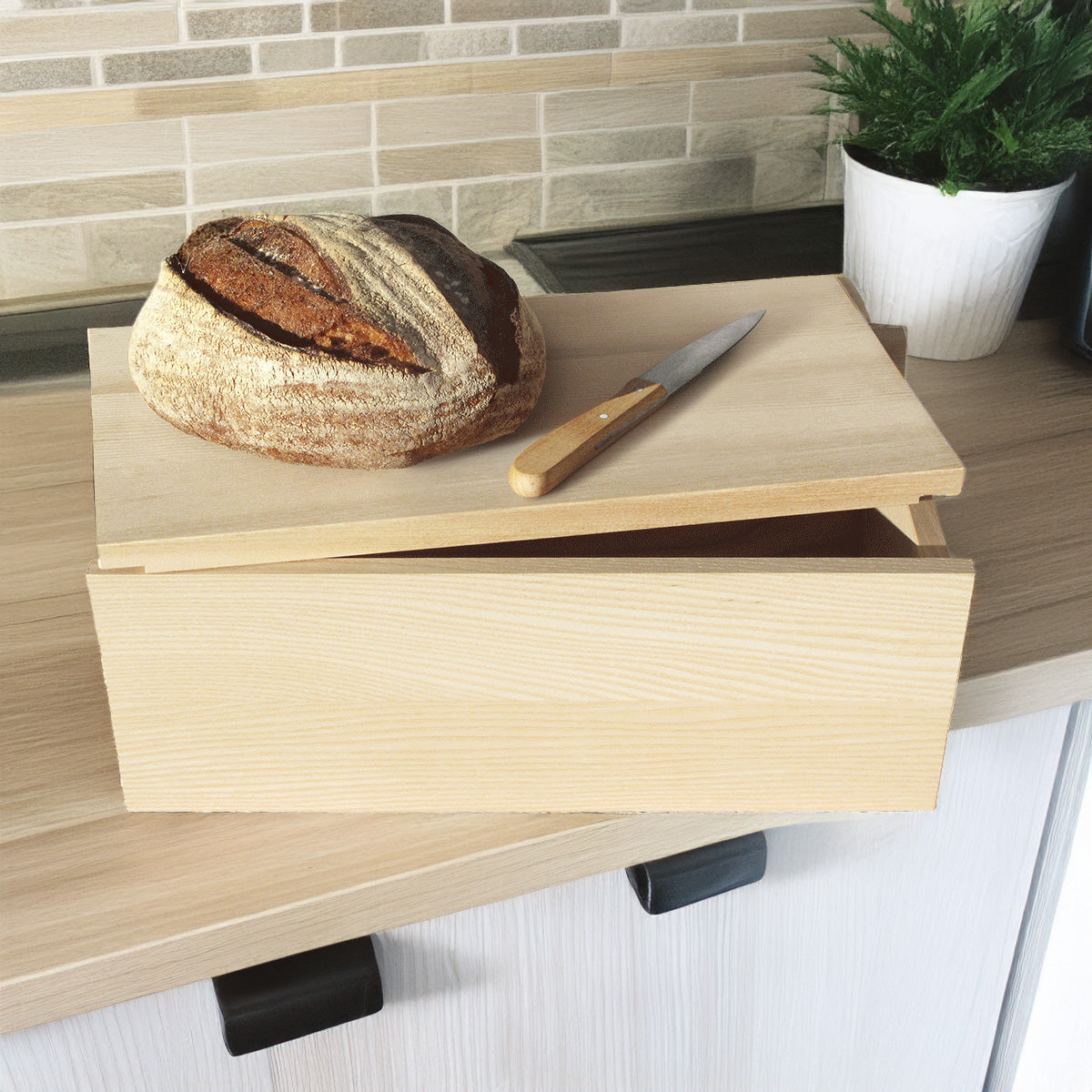 Brotdose; Deckel oben leicht geöffnet: Auf ihm ein Laib Brot und Messer